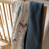 Dog Park swaddle and navy blanket hanging on a crib